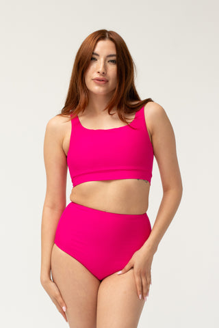 Front view of model wearing a POST SWIM pink bikini set with square neck bikini top and tummy control high waisted bikini bottom.