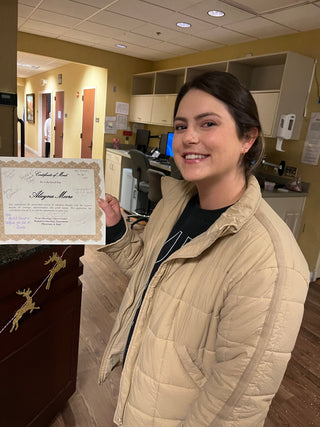 Alayna Moore smiling and holding her Certificate of Merit from the Texas Oncology Cancer Center Radiation Oncology Department, marking the completion of her radiation therapy.