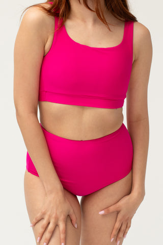 Front view of model wearing a POST SWIM pink tummy control bikini bottom with matching bikini top.