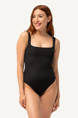 Woman wearing a black swimsuit on a plain background