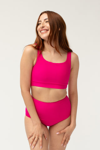 Front view of model wearing a POST SWIM pink tummy control bikini bottom with matching bikini top.